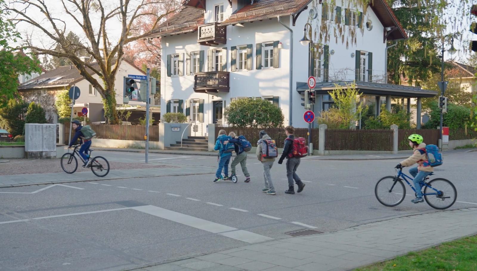 Schüler und Lehrkräfte versammeln sich auf dem sonnigen Schulhof der Grundschule, um gemeinsam die Erfolge der autofreien Meilensteine zu feiern.